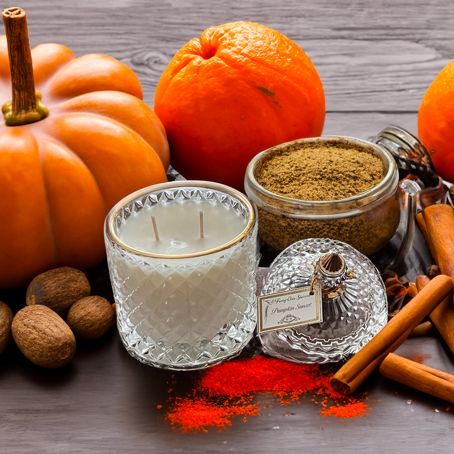 Pumpkin Sunset scented candle in clear glass jar with gold label
